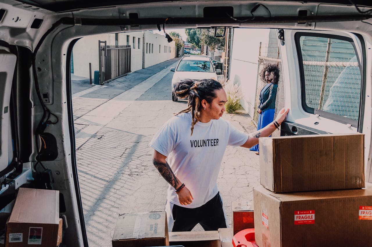 Volunteers organizing and distributing donations from a van on a community street.