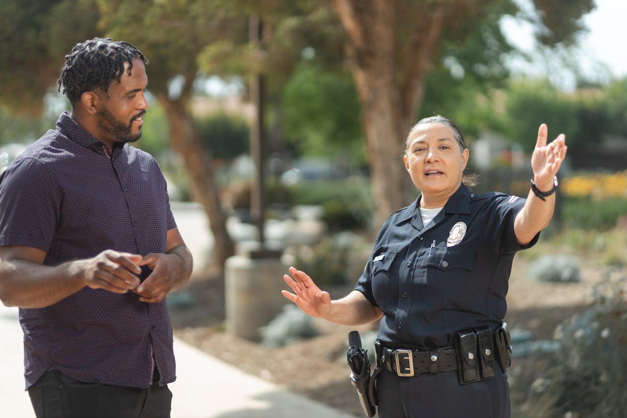 Police officer in uniform engaging in a conversation with a man on a sunny day, promoting community relations.